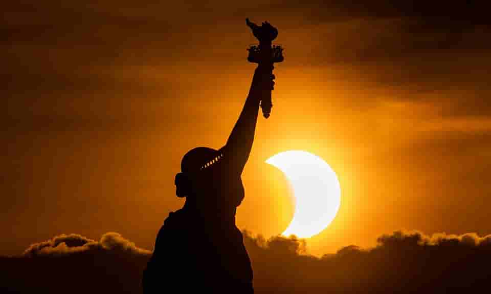 Image of Eclipse behind Statue of Liberty.